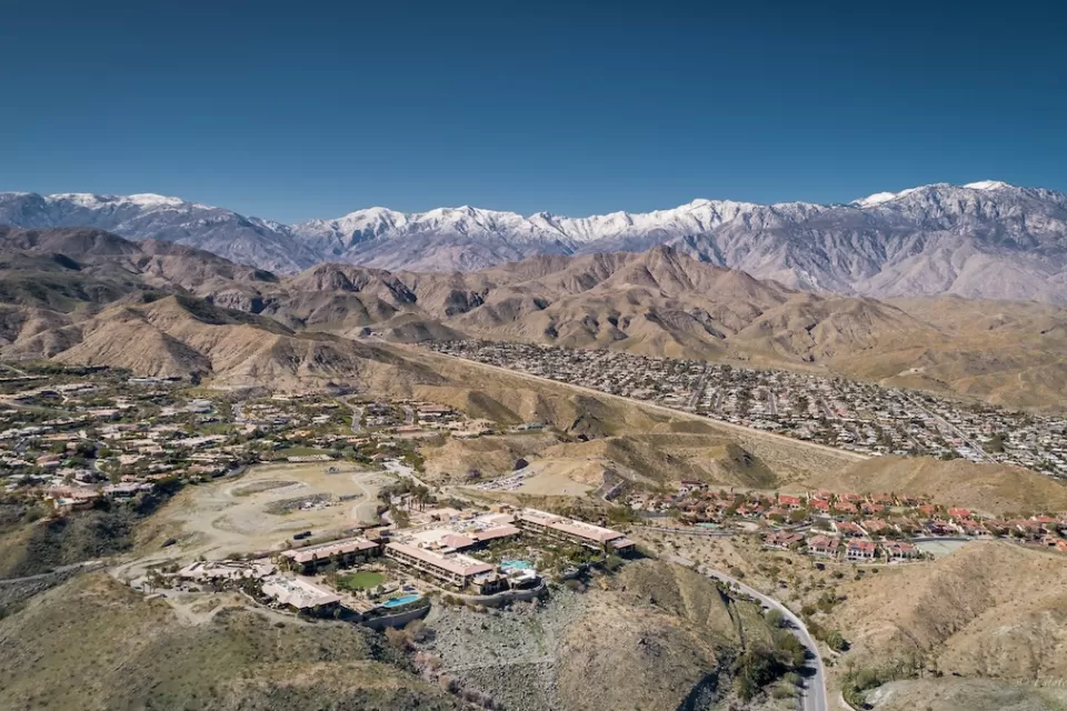 Aerial view of Rancho Mirage, California with homes in foreground and snowy San Gabriel Mountains in background.
